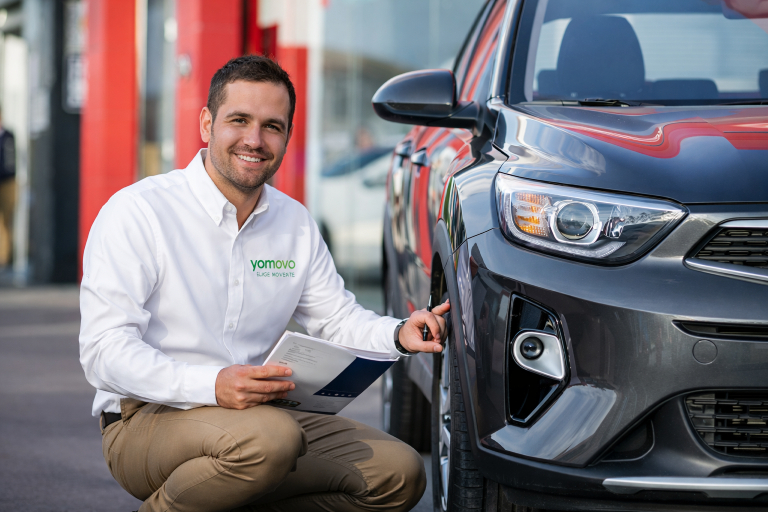 asesor yomovo agachado al lado de un coche